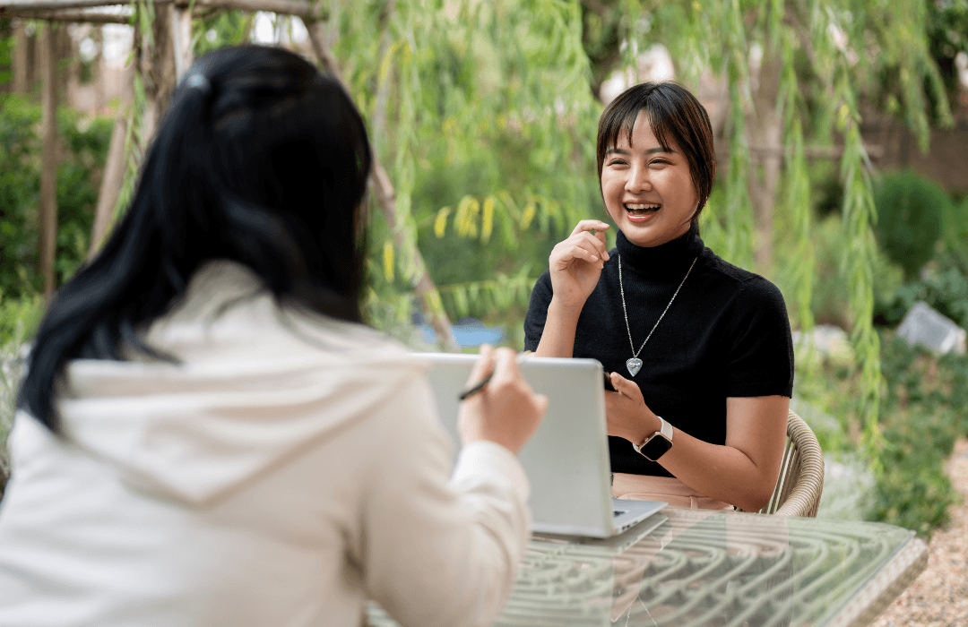 Two women sitting and talking about retreat personal branding strategies.