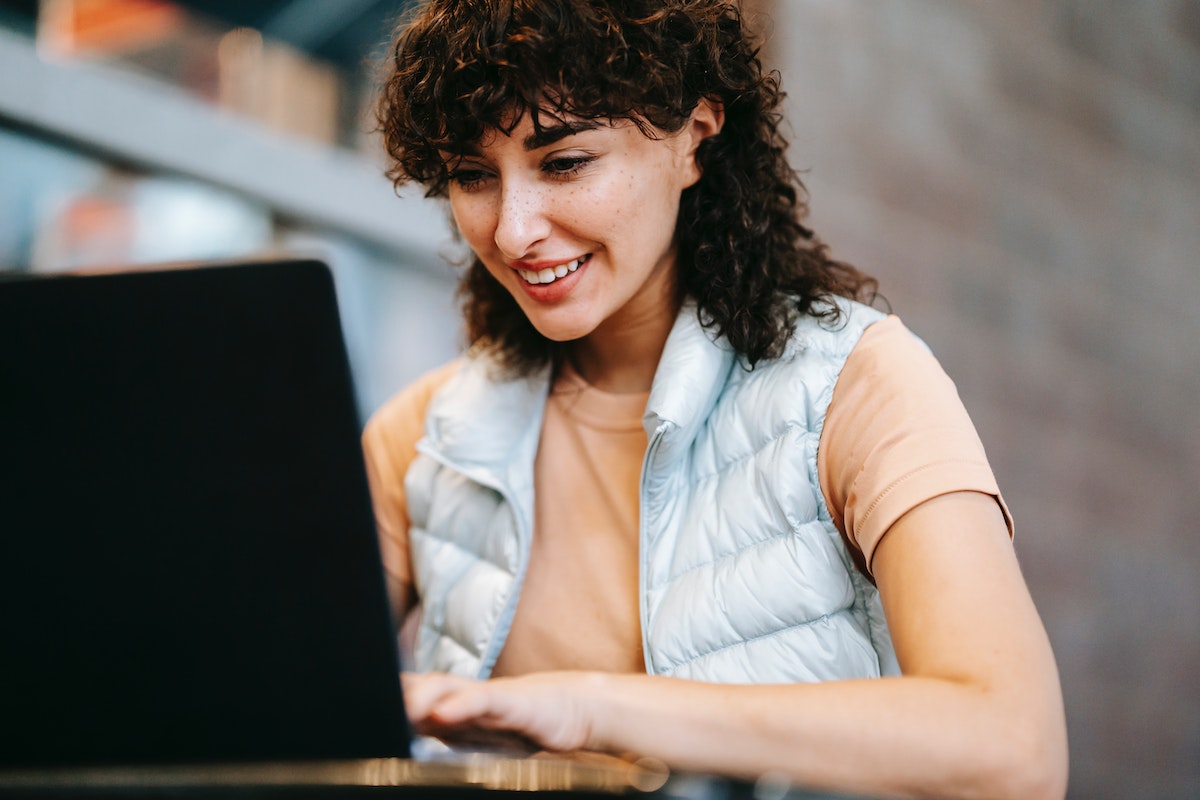 A woman setting up a booking system on a black laptop.