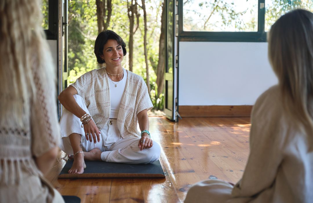 A wellness retreat leader sitting and talking to her clients.